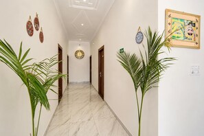 Un pasillo con piso de mármol, puertas a ambos lados y adornos en las paredes.