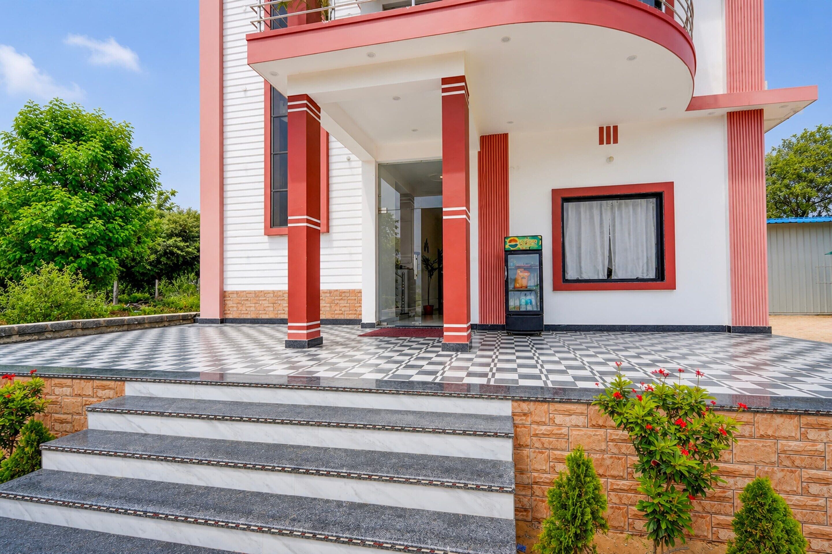 Un edificio moderno con suelo a cuadros, una escalera que conduce a la entrada y una puerta de vidrio.