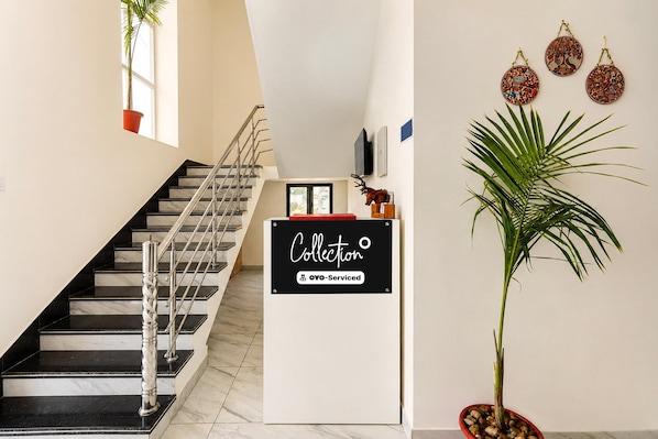 Una escalera con barandilla, un cartel que dice 'Collection OYO-Serviced' y una planta en maceta.