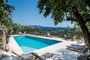 Ein rechteckiger Pool mit Holzterrasse, umgeben von Liegestühlen und einem Holzzaun.