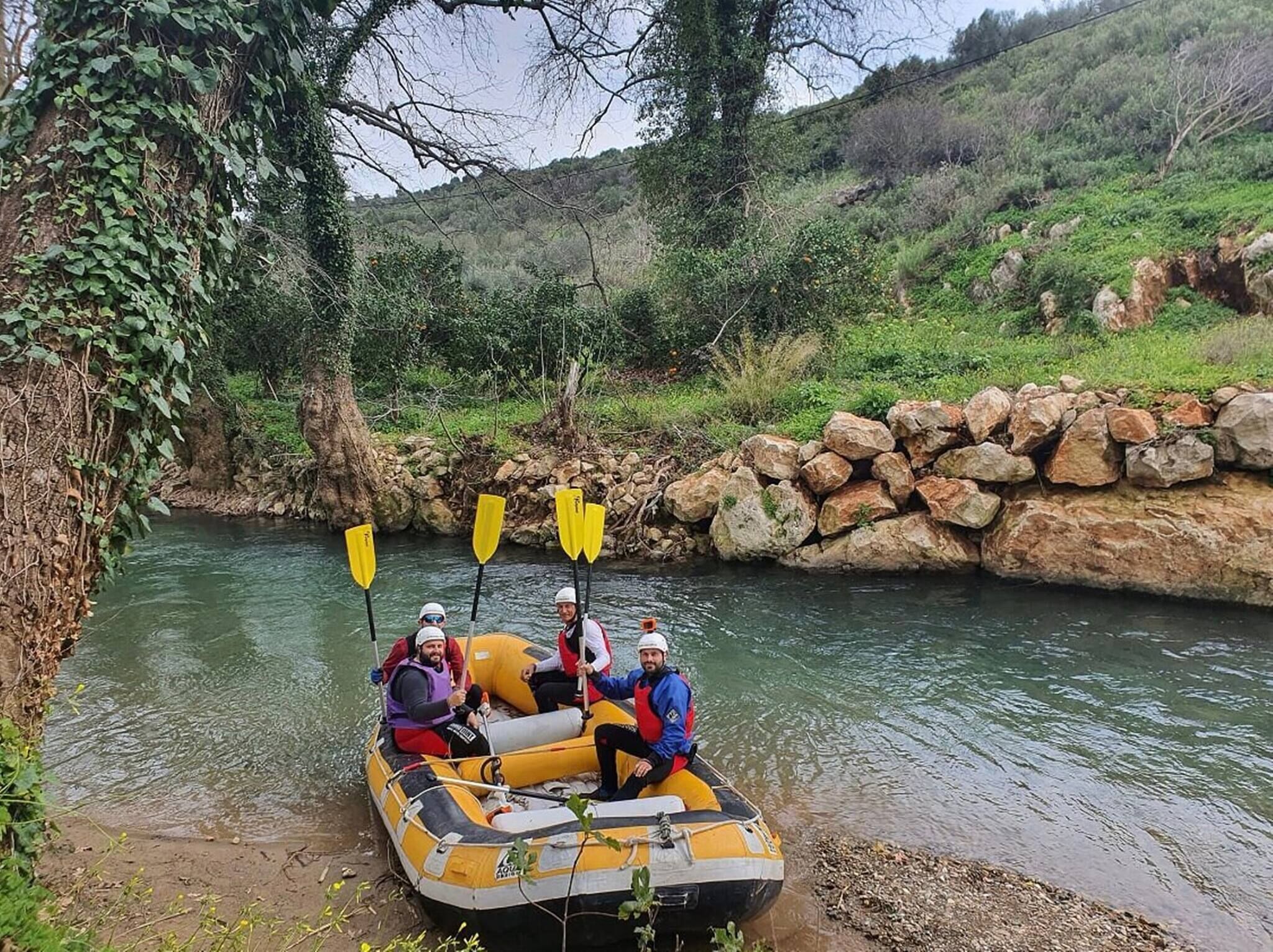 A group of people in a yellow inflatable raft on a river surrounded by greenery and rocks.