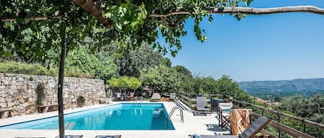 Ein Poolbereich mit Liegestühlen und einer Steinmauer.