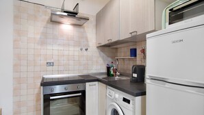 Uma cozinha compacta com forno embutido, máquina de lavar e geladeira.