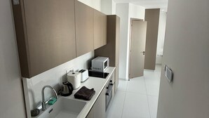 Eine moderne Küche mit weißer Arbeitsplatte, Edelstahlgeräten und einer grauen Spritzschutzwand.