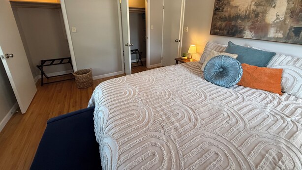 A bedroom with a large bed, a painting on the wall, and a closet with a bench. - The Brick Haven in Brookings - spacious home in a central location! (Brookings)