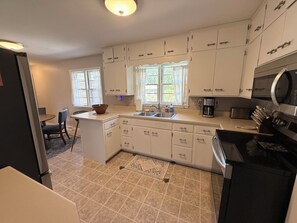A compact kitchen with white cabinets, a built-in oven, and a coffee maker. - The Brick Haven in Brookings - spacious home in a central location! (Brookings)