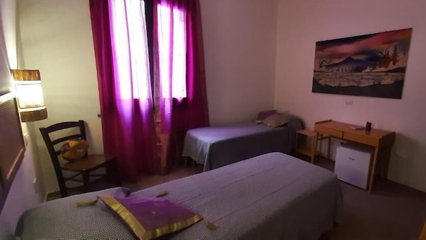 A room with two beds, a desk, a chair, a small cabinet, and a painting on the wall. - PROFUMO DI CALICANTO B&B (Tresnuraghes)
