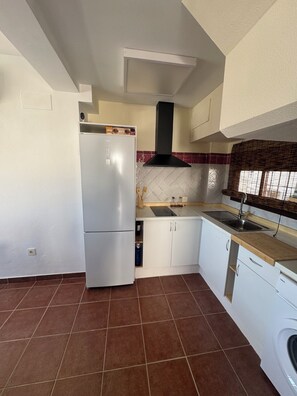 Eine Küche mit einem weißen Kühlschrank, einem Herd, einer Spüle und einem Geschirrspüler.