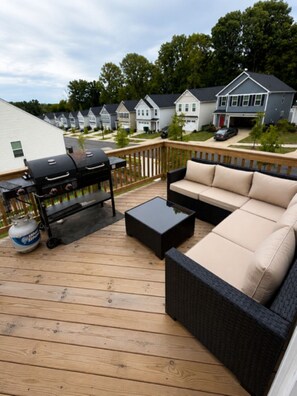 Eine Terrasse mit Grill, einer Sitzecke und einem Couchtisch.