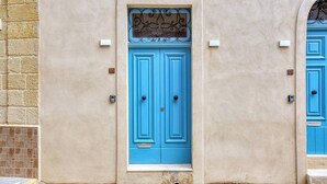 Eine Gebäudefassade mit einer blauen Tür, der Hausnummer 25, und einem kleineren Fenster darüber.