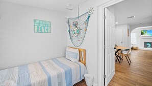 Un dormitorio con cama, decoración en la pared, una puerta que da a otra habitación y un televisor al fondo.