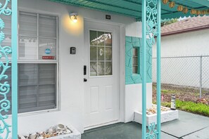 A white door with a 'Beware of Dog' sign, a mailbox, and a small garden area with a white planter and a birdbath. - AC. Private 2-Unit property near the beach & 5th Ave South in Downtown Naples (Naples)