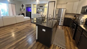 Une cuisine moderne dotée d’un îlot central, d’appareils électroménagers en acier inoxydable et d’un tapis à motifs à carreaux.
