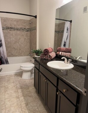 Ein Badezimmer mit Badewanne, Toilette, Waschbecken und Spiegel.