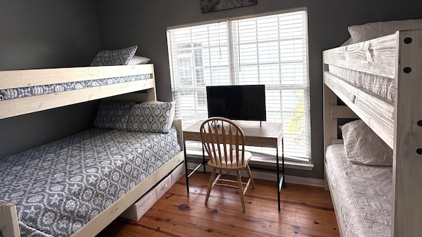A dorm-style room with bunk beds, a desk, a chair, and a ceiling fan. - Drift Away, a Charming Coastal Cottage with pool and hot tub (Gulf Shores)