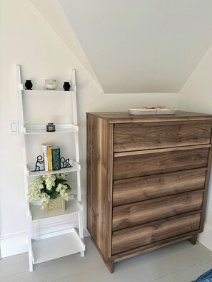A white shelving unit with decorative items and a wooden dresser with drawers. - Beautiful well appointed upstairs condo in old Victorian (Rockland)
