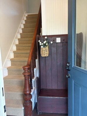 A wooden staircase with a dark door and a basket of white flowers. - Beautiful well appointed upstairs condo in old Victorian (Rockland)