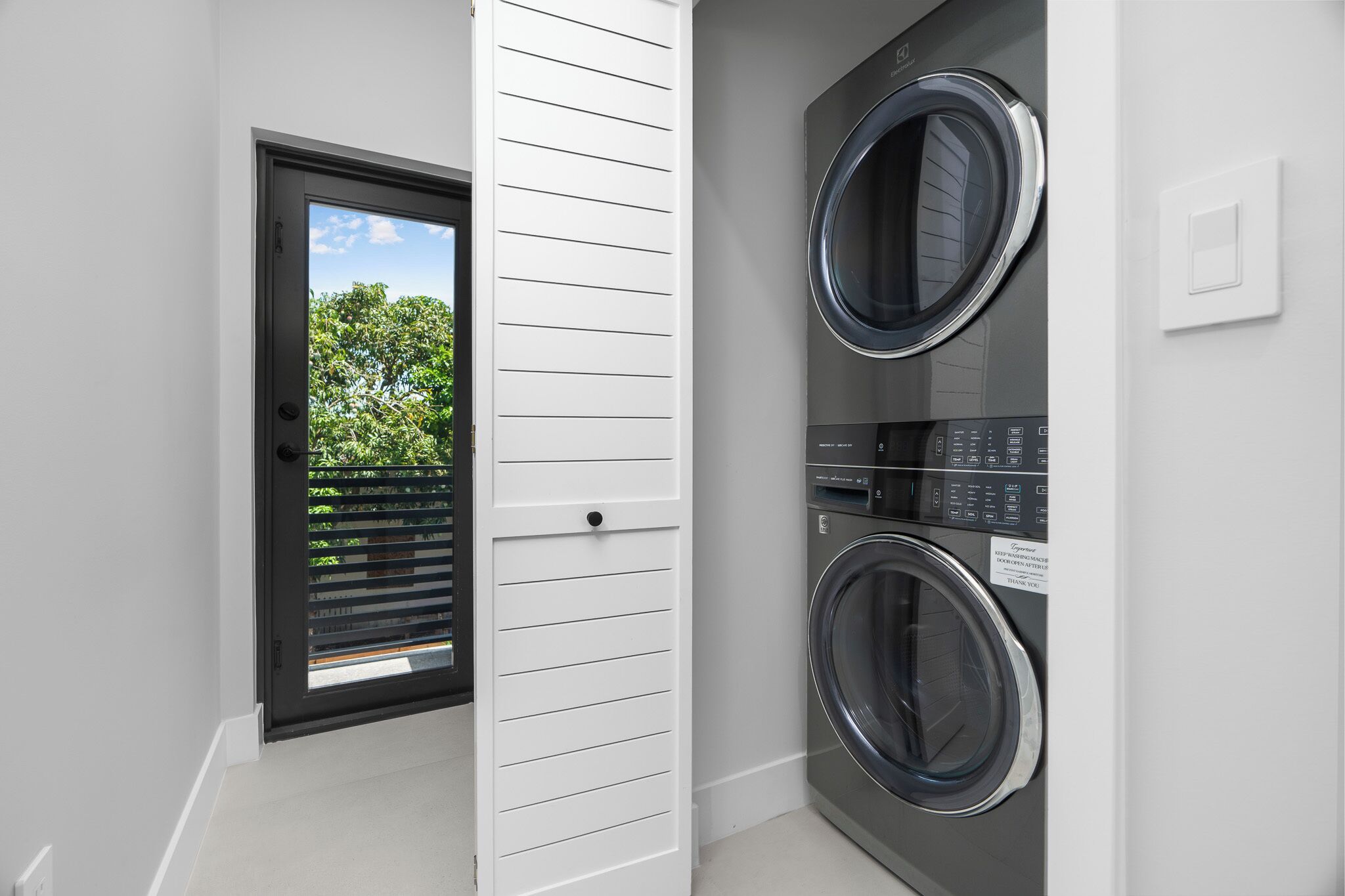 Una sala de bugaderia amb dues rentadora frontals, una porta que dóna a l'exterior i una paret blanca.
