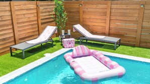 Ein Swimmingpool mit zwei Liegestühlen und einem rosa Luftmatratze.