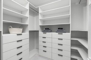 Un placard blanc avec plusieurs étagères et tiroirs, un panier et des serviettes pliées.