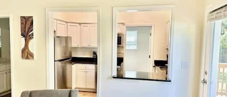 A modern kitchen with white cabinets, a stainless steel refrigerator, and a black countertop.
