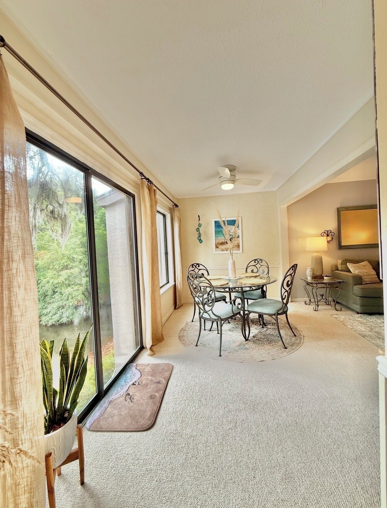 A spacious room with a dining area, large windows, and a ceiling fan.