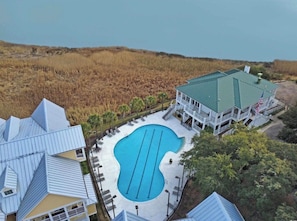 Un complexe hôtelier doté d’une piscine, d’un bâtiment surmonté d’un toit végétalisé et offrant une vue sur la plage.