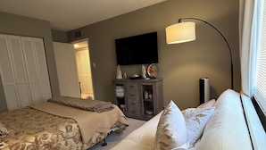 Un dormitorio con dos camas, un aparador, un televisor y una lámpara.