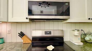 A kitchen with a stainless steel stove, a microwave above it, and white cabinets.
