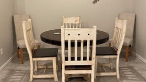A dining area with a round table, four chairs, and a wall-mounted sign. - Family Fun Meets Cozy Comfort - 3 Bedrooms, 2 Bathrooms, Game Room and Hot Tub! (Odessa)