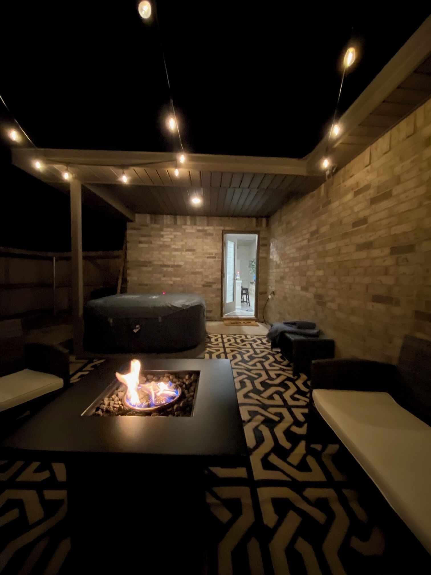 A modern relaxation area with a fire feature, seating, and a view of the outside.