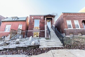 A row of red brick townhouses with a central staircase leading to a front door. - The Lions Lair - New loft style home in STL (St. Louis)