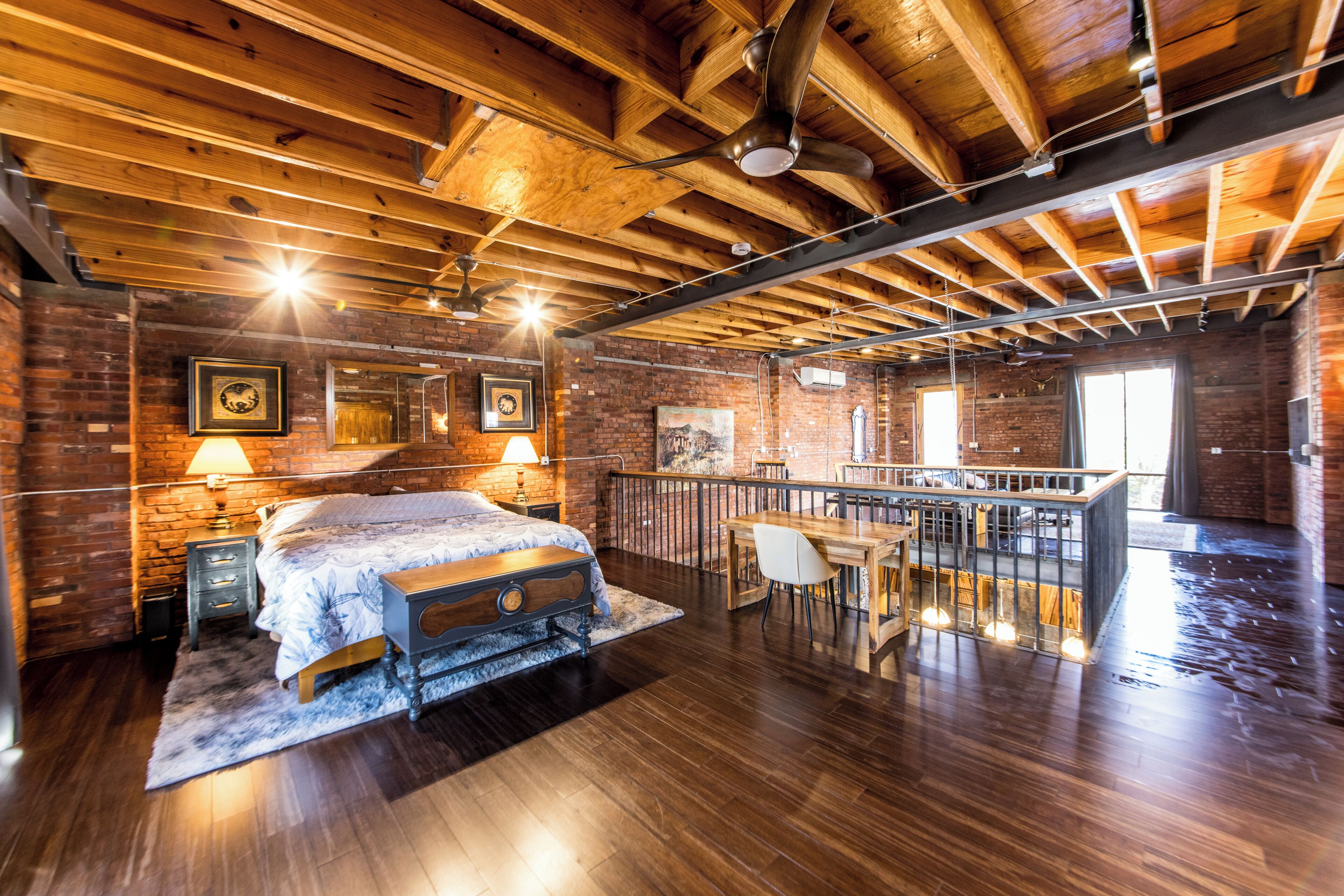 Een ruime slaapkamer met een groot bed, een bureau en een balkon.