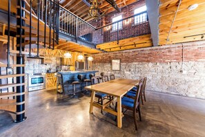 A spacious kitchen with modern appliances, a bar area with stools, and a dining table with chairs. - The Lions Lair - New loft style home in STL (St. Louis)