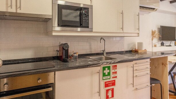 Una cocina moderna con armarios blancos, un microondas de acero inoxidable y piso de madera.