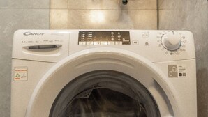Una lavadora de carga frontal con panel de control, un adhesivo de garantía Paris de 10 años y una puerta de carga frontal.
