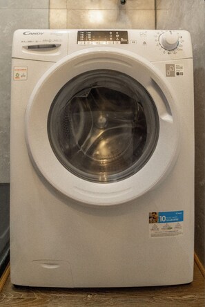 A front-loading washing machine with a control panel, a 10-year Paris guarantee sticker, and a front-loading door. - Bairro Alto Studio 2 · Right in the Heart of the City · AC (Lisboa)