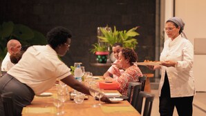 Un groupe de personnes est assis à une table, et un serveur leur apporte à manger.