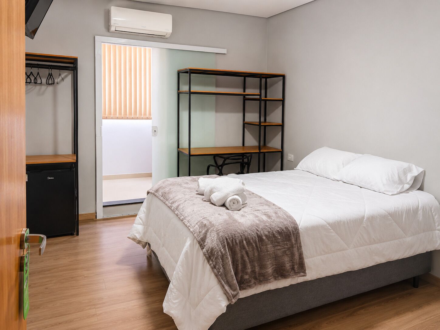 A bedroom with a bed, a desk, and a wardrobe.