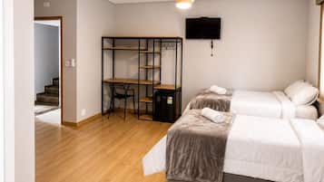 Une chambre avec deux lits, un bureau et une télévision.