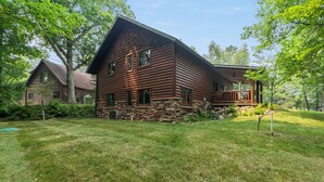 A log cabin with a stone foundation, a porch, and a well-maintained lawn. - Handcrafted 4BR Cabin on Rabbit Lake, Aitkin (Aitkin)