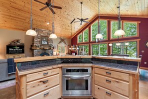 A kitchen with a large island, built-in oven, and pendant lights.