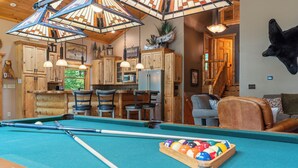 A pool table with pool cues and balls, wooden cabinets, a fireplace, and a mounted animal head. - Handcrafted 4BR Cabin on Rabbit Lake, Aitkin (Aitkin)