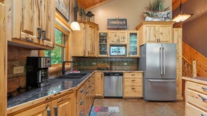 A kitchen with wooden cabinets, a stainless steel refrigerator, a coffee maker, and a dishwasher. - Handcrafted 4BR Cabin on Rabbit Lake, Aitkin (Aitkin)