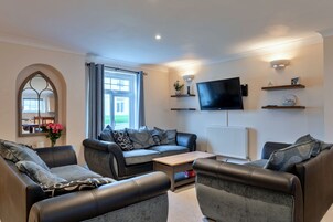 Una sala de estar moderna con un conjunto de sofás, un televisor de pantalla plana y estantes decorativos.