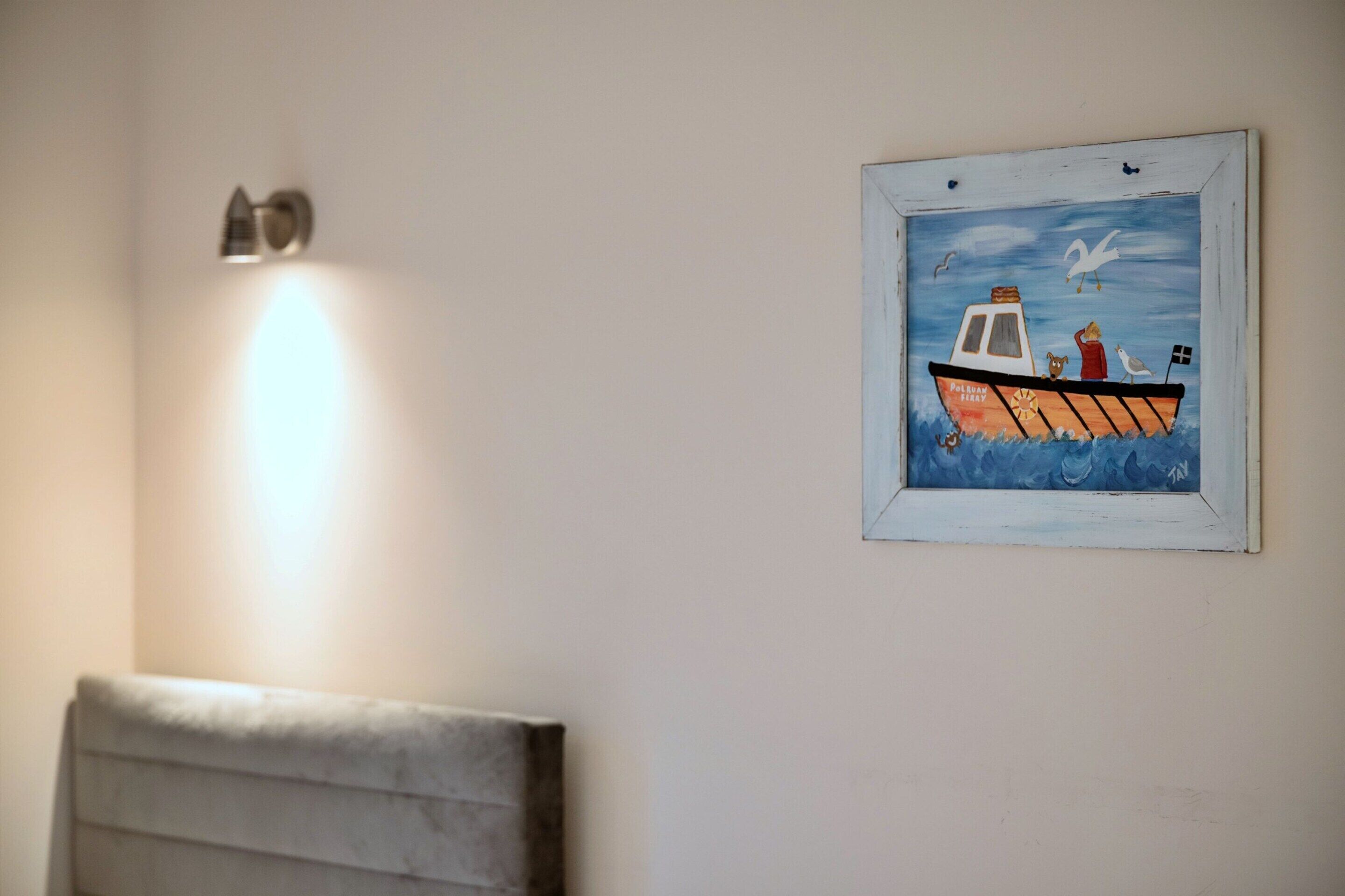 A framed painting of a boat with a flag and a seagull on the wall.