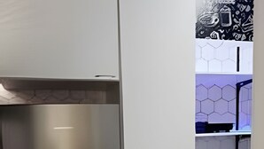Une cuisine dotée d’un réfrigérateur en acier inoxydable, de meubles blancs et d’un dosseret à motifs hexagonaux.