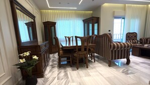 A spacious room with a dining area, a sofa, and a large mirror. - Luxury 3-Bedroom Family Apartment, Prime Location, Free WiFi & Free Parking (Amman)