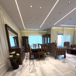 A spacious room with a dining area, a sofa, and a large mirror. - Luxury 3-Bedroom Family Apartment, Prime Location, Free WiFi & Free Parking (Amman)