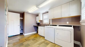 Une buanderie équipée d’un lave-linge, d’un sèche-linge et de placards.